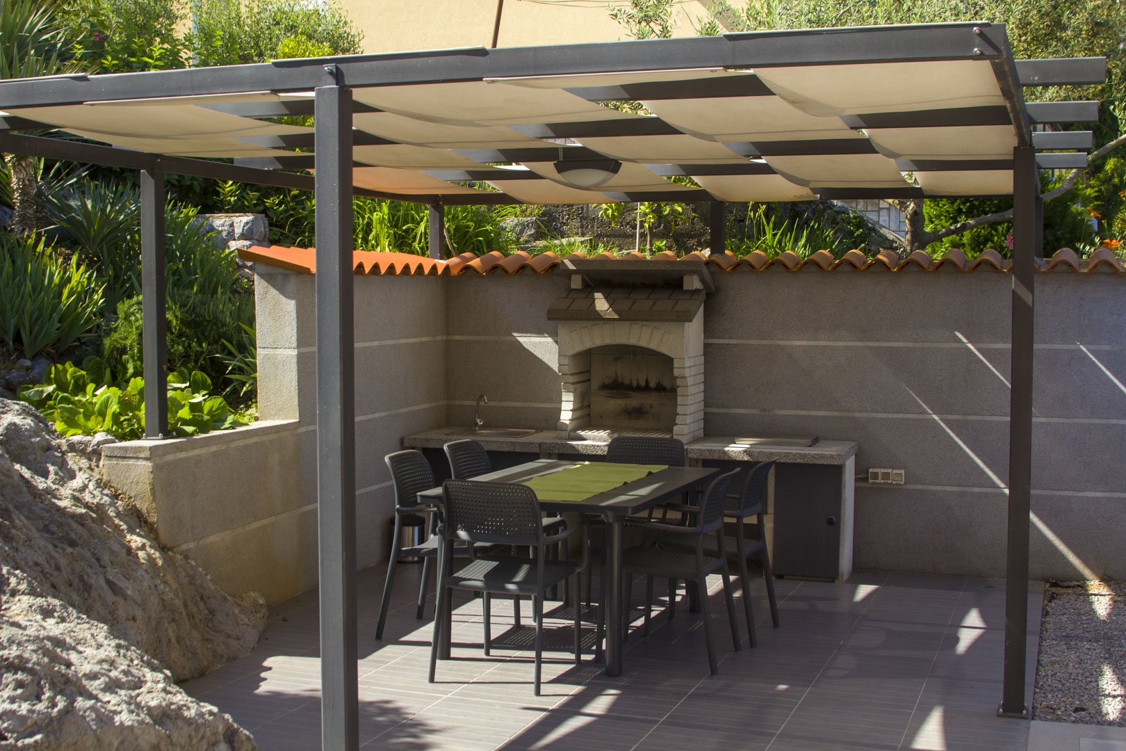 Covered outdoor barbecue area with dining space at Holiday Home Salvia